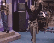 a man is dancing on a stage in front of a television in a room .