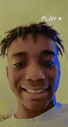 a young man with dreadlocks is smiling with a play button in the background