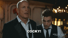 a man in a suit says cocky in front of another man