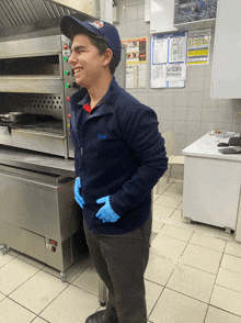 a man wearing a domino 's hat and gloves smiles in a kitchen