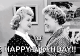 two women are standing next to each other in a living room and talking to each other .