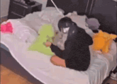 a person is sitting on a bed with a stuffed animal in their lap .