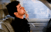 a man in a car with a teddy bear in his mouth and a cigarette in his mouth