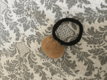 a black and brown hair tie is laying on a floral patterned fabric