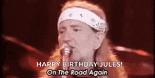 a man singing into a microphone with the words `` happy birthday jules on the road again '' .