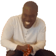 a man in a white shirt is sitting on the floor and smiling .