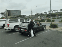 a man is standing next to a black car with a license plate that says jcv - jcv