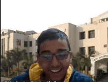 a young man wearing glasses is smiling in front of a large building that says amity international