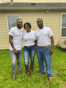 three people posing for a picture in front of a house