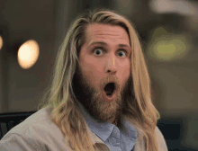 a man with long blonde hair and a beard has his mouth wide open