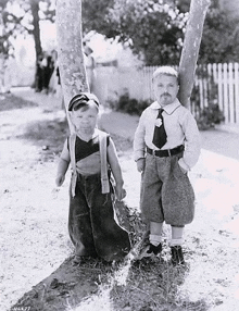 two little boys are standing next to each other in a black and white photo .