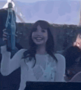 a woman is holding a bottle of water in her hand while smiling .