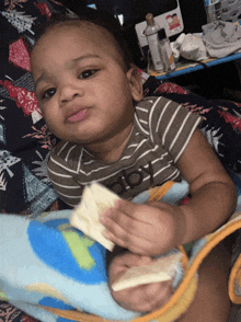 a baby is laying on a blanket and eating a piece of bread