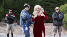 a man wearing a hat that says supreme stands next to a woman in a red dress