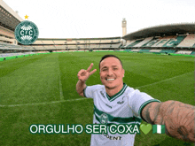 a man taking a picture of himself in front of a soccer field with orgulho ser coxa written on the bottom