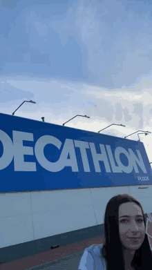 a woman is standing in front of a large decathlon sign