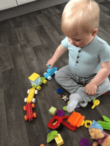 a baby is sitting on the floor playing with lego blocks