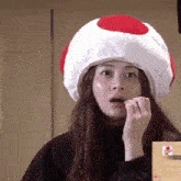 a woman wearing a mushroom hat is eating something