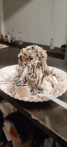 a scoop of chocolate ice cream on a paper plate with a spoon