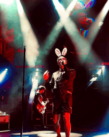 a man wearing bunny ears is singing into a microphone on stage