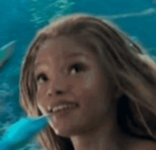 a young girl is smiling and looking up at the sky while swimming in the ocean .