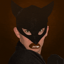 a person wearing a cat mask with a black blanket around their neck