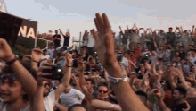 a crowd of people raising their hands in the air in front of a sign that says na on it