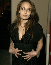 a woman in a black dress is holding her stomach