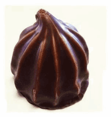 a close up of a dark chocolate marshmallow on a white surface .