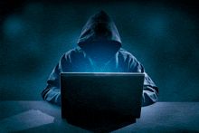 a person in a hoodie is using a laptop computer