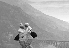 a man and a woman are dancing in front of a mountain