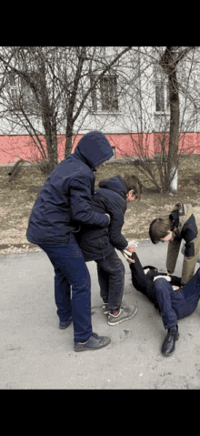 a man in a hooded jacket is holding another man 's arm