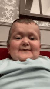 a baby with a blue shirt on is smiling and making a funny face