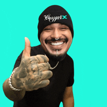 a man wearing a black beanie with the word blizzard on it gives a thumbs up