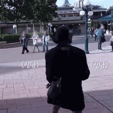 a woman in a black coat is walking down a sidewalk in front of a building with chinese writing on it