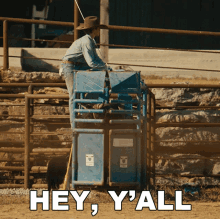 a man in a cowboy hat is sitting in a chute with the words " hey y'all " written below him