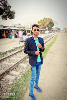 a man in a suit stands in front of train tracks with the word tecno on the bottom