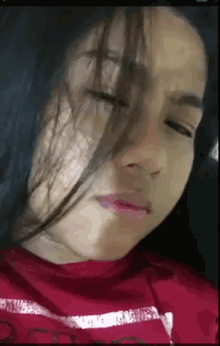 a close up of a woman 's face with her eyes closed and a red shirt on