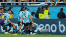 a group of soccer players are playing on a field in front of a sign that says ' sports ' on it .