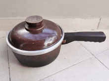 a brown pot with a lid and a handle on a tiled floor