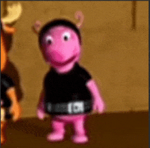 a pink teddy bear is wearing a black shirt and a black belt .