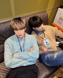 two young men are sitting on a couch and one of them has a name tag that says ' aoa ' on it