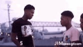 three young men are standing next to each other in front of a bridge .