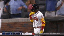 a baseball player wearing a helmet and gloves stands in front of a scoreboard that says " coming up next "