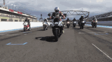 a group of people riding motorcycles on a track with a sign in the background that says ' fox racing '