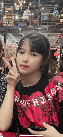 a girl wearing a red t-shirt with the word revolution on it is giving a peace sign