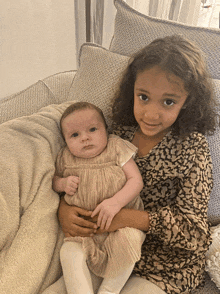 a little girl holds a baby in her arms