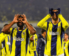 two soccer players wearing yellow and blue uniforms with otokoc on them