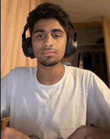 a young man wearing headphones and a white shirt looks at the camera