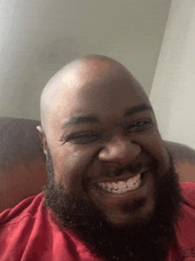 a man with a beard wearing a red shirt smiles